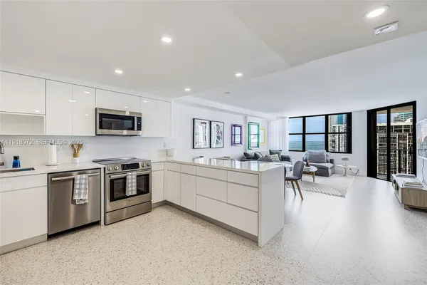 a large white kitchen with white cabinets and stainless steel appliances
