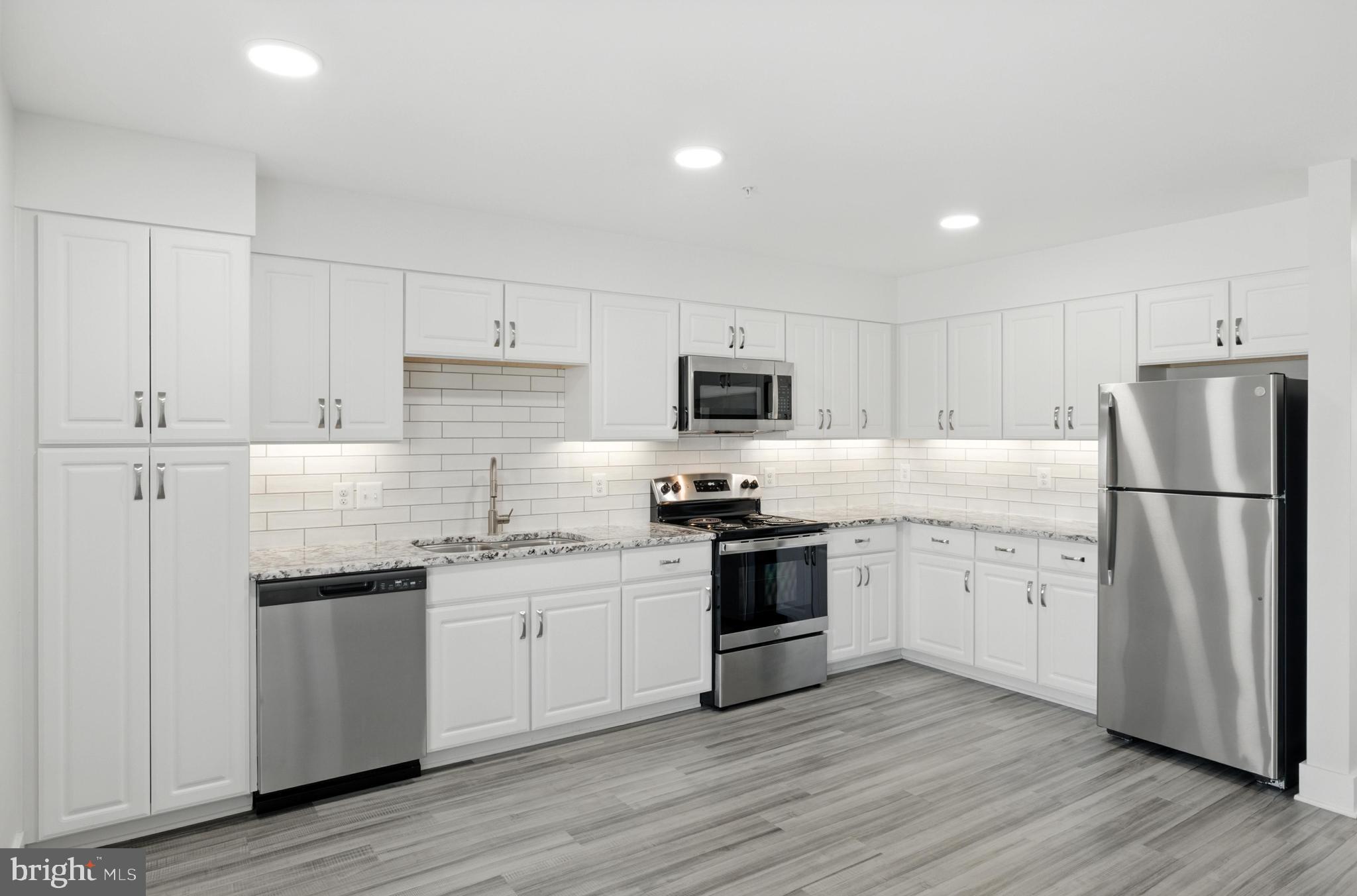 19510 Village Walk, Unit 2205 Montgomery Village, MD 20886 - Photo 5 of 21 a kitchen with granite countertop white cabinets and stainless steel appliances