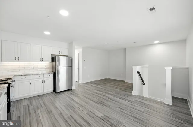 a view of a kitchen with refrigerator and wooden floor