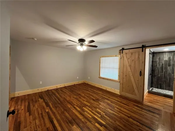 an empty room with wooden floor chandelier fan and windows
