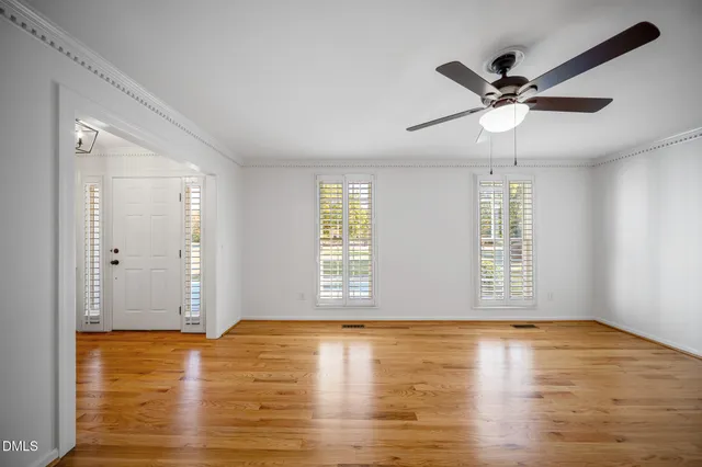 a view of an empty room with window and wooden floor