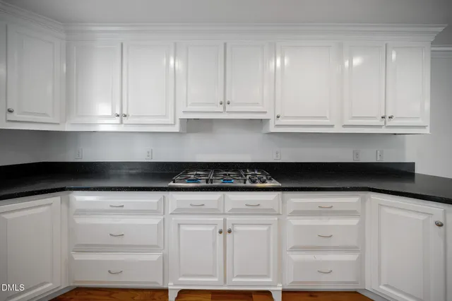 a kitchen with granite countertop white cabinets and a stove
