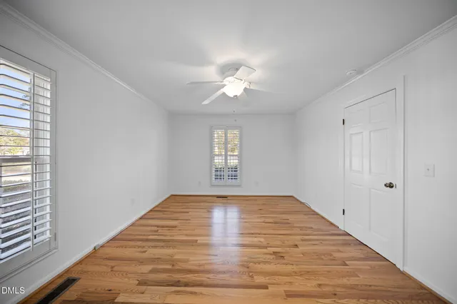a view of an empty room and window and chandelier fan