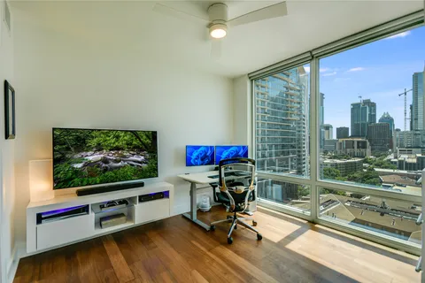 a view of a livingroom with furniture a flat screen tv and floor to ceiling window