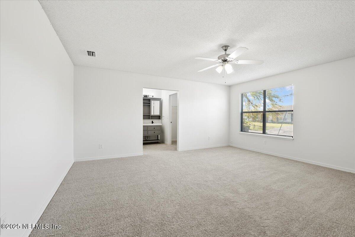 8215 Sailmaker Lane Jacksonville, FL 32210 - Photo 13 of 29 an empty room with chandelier fan and windows