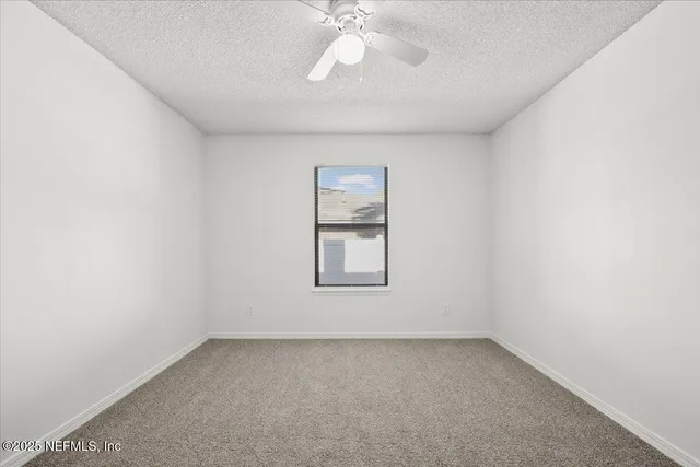 an empty room with a window and a fan