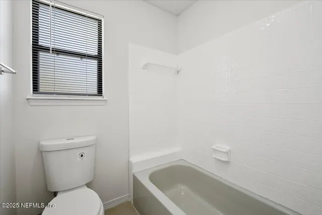 a white toilet sitting next to a bath tub