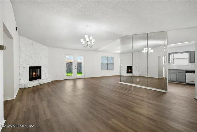 a view of empty room with wooden floor and kitchen view