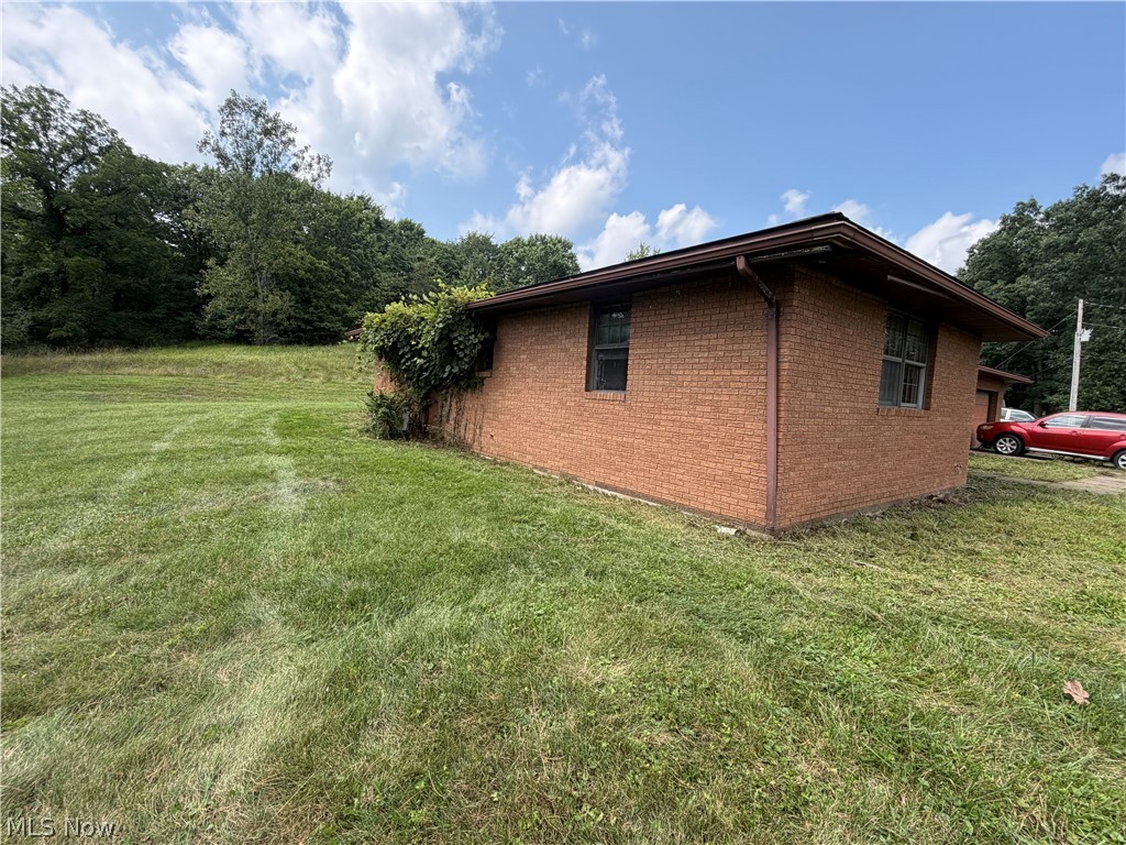 3260 Tabor Ridge Road Northeast Mineral City, OH 44656 - Photo 23 of 27 Brick exterior with a brown roofline, featuring multiple windows and a surrounding green landscape