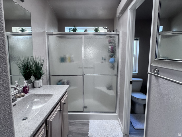 2815 Gordon Creek Road Price, UT 84501 - Photo 5 of 13 Bathroom featuring a shower with frosted sliding glass doors, a vanity with an integrated sink and speckled countertop, and wood-finish flooring