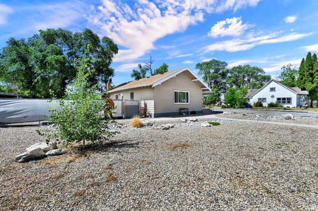 716 East Factory Street Garland, UT 84312 - Photo 3 of 30 Low-maintenance gravel landscaping with a young deciduous tree and decorative boulders