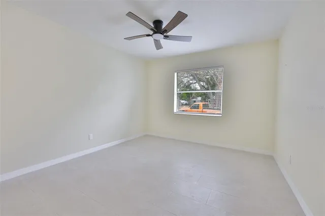 an empty room with a window and a ceiling fan