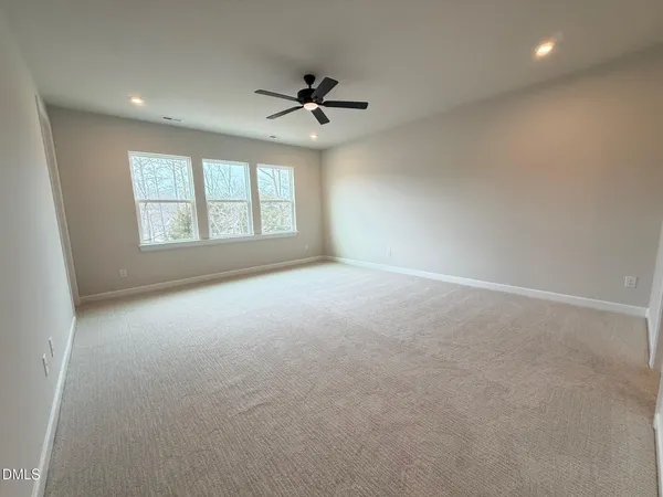 an empty room with a ceiling fan and windows