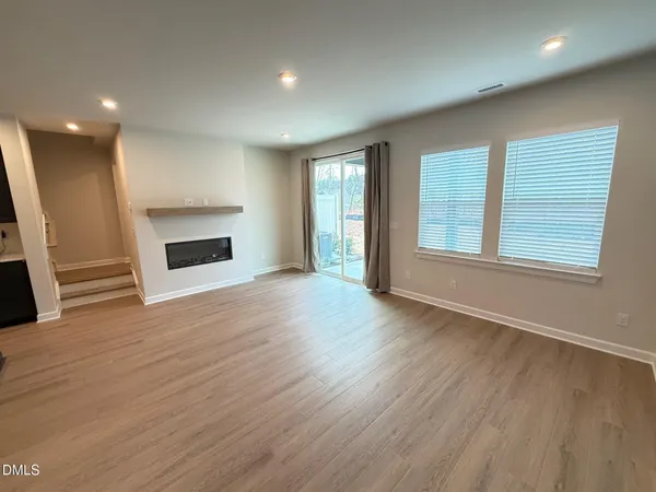 an empty room with wooden floor fireplace and windows