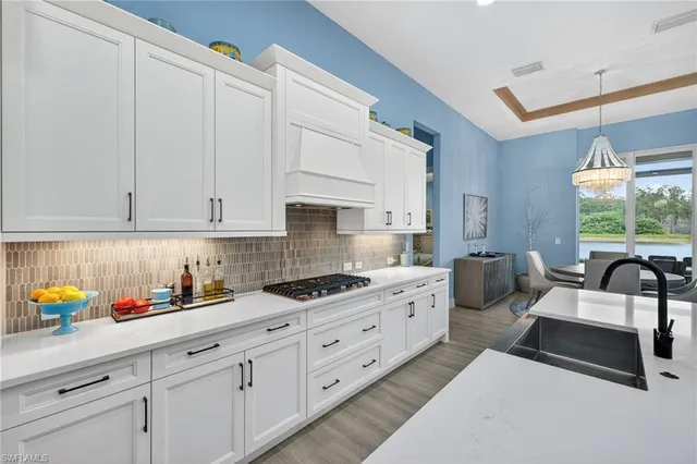 a kitchen with stainless steel appliances granite countertop a sink a stove and white cabinets