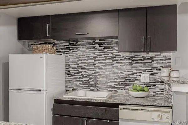 a kitchen with granite countertop a sink and a refrigerator