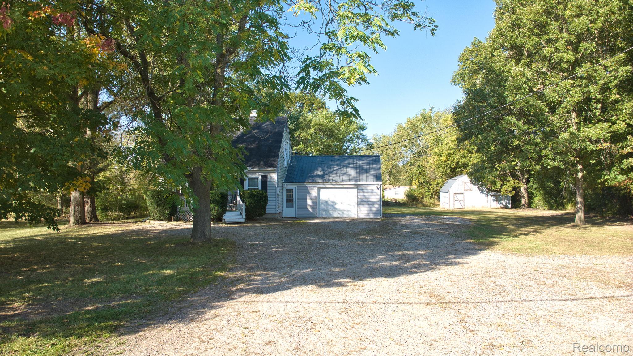 4455 North Genesee Road Flint, MI 48506 - Photo 36 of 47 View of side of home with driveway, a lawn, and a storage shed
