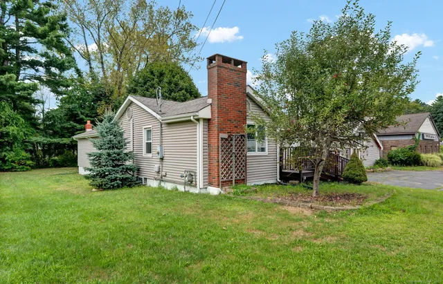 a view of a house with a yard and large tree