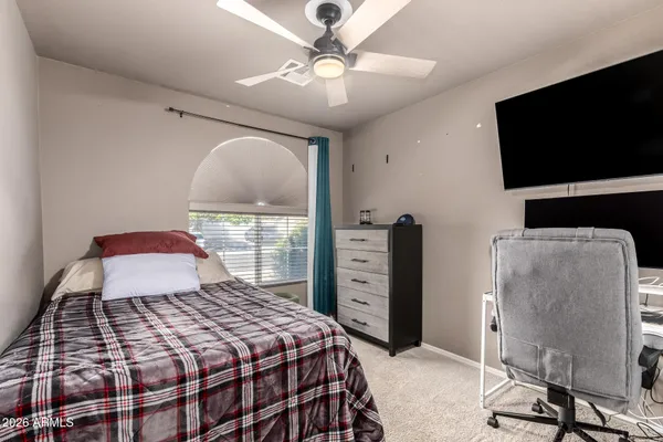a bedroom with a bed and a flat tv screen on dresser