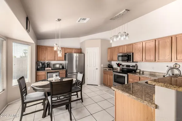 a kitchen with stainless steel appliances granite countertop a stove top oven a sink dishwasher a dining table and chairs with wooden floor