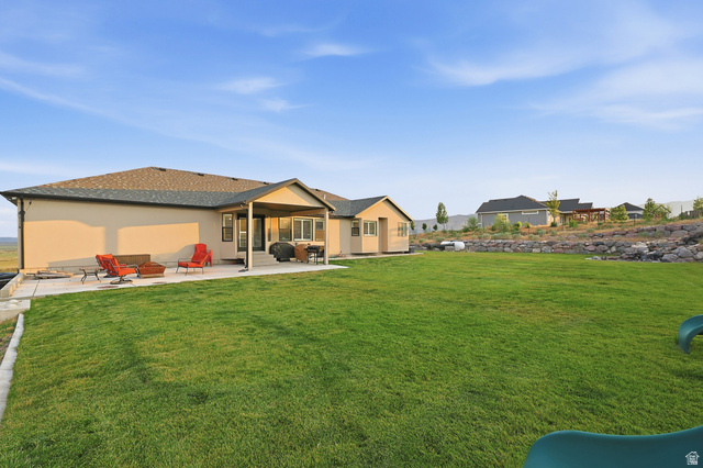 2056 West Ridgeline Road Stockton, UT 84071 - Photo 5 of 50 Expansive backyard featuring a large green lawn, concrete patio, and a covered patio area