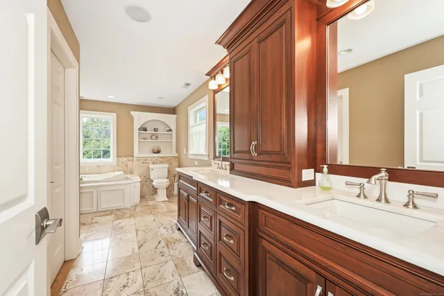a spacious bathroom with a double vanity sink a large mirror and a bathtub