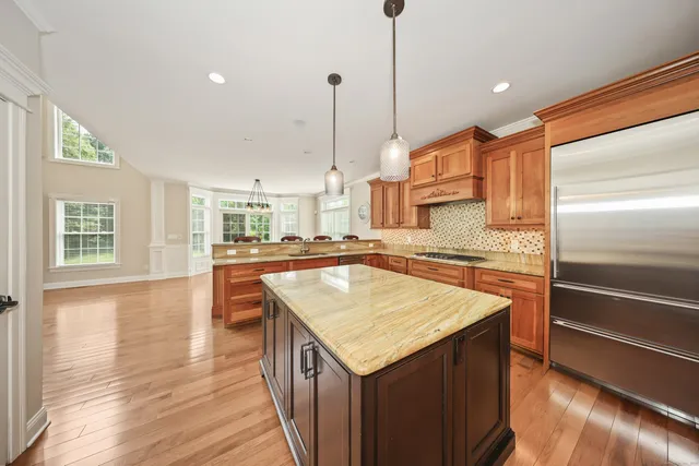 a kitchen with stainless steel appliances granite countertop a kitchen island a stove a sink and a refrigerator