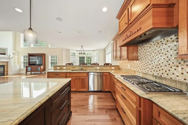 a kitchen with stainless steel appliances granite countertop a sink a stove and a wooden floors