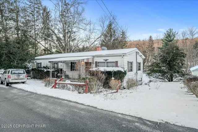 a view of a patio with table and chairs under an umbrella with large trees