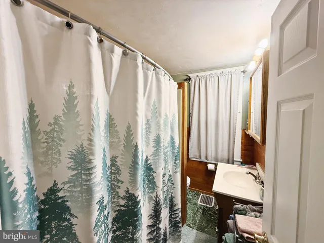 a bathroom with a shower curtain and a chair