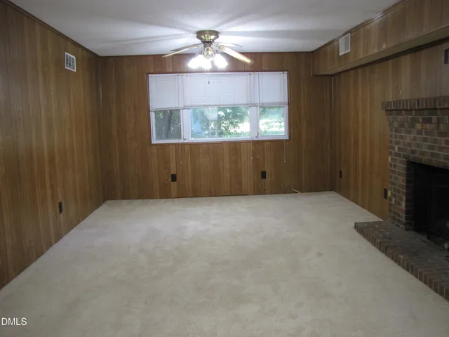 a view of an empty room with a fireplace and a window