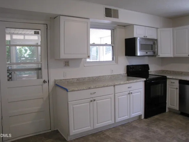 a kitchen with white cabinets and window