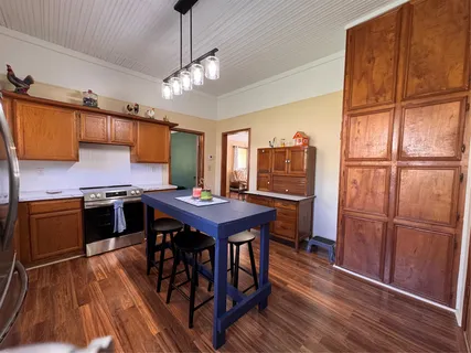 a kitchen with stainless steel appliances granite countertop a refrigerator a stove a sink dishwasher and a dining table with wooden floor