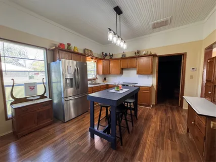 a kitchen with stainless steel appliances a refrigerator a stove a sink dishwasher a dining table and chairs with wooden floor