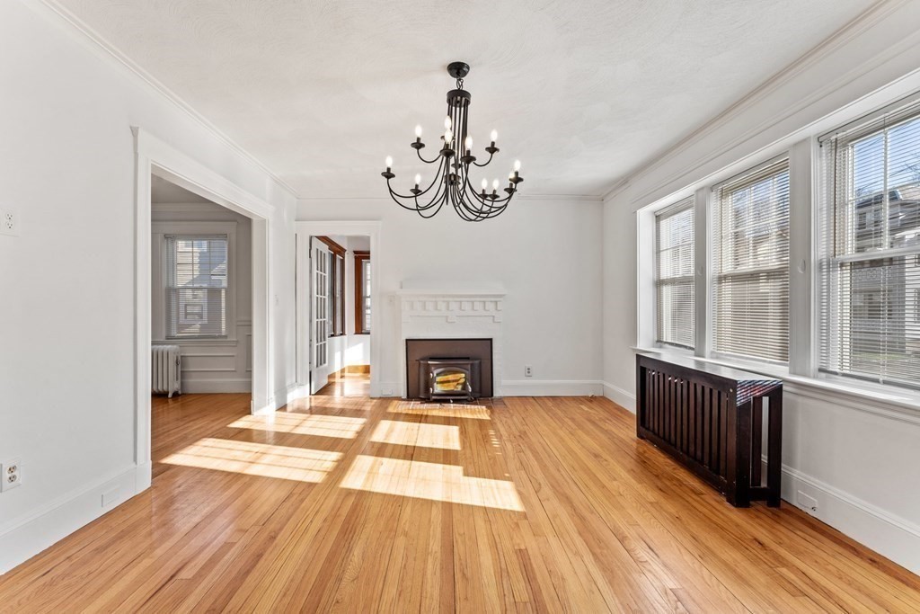 54 Chester Road, Unit 1 Belmont, MA 02478 - Photo 3 of 31 a view of an empty room with wooden floor fireplace and a window