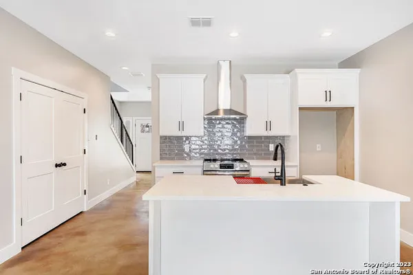 a kitchen with stainless steel appliances a stove a sink and white cabinets