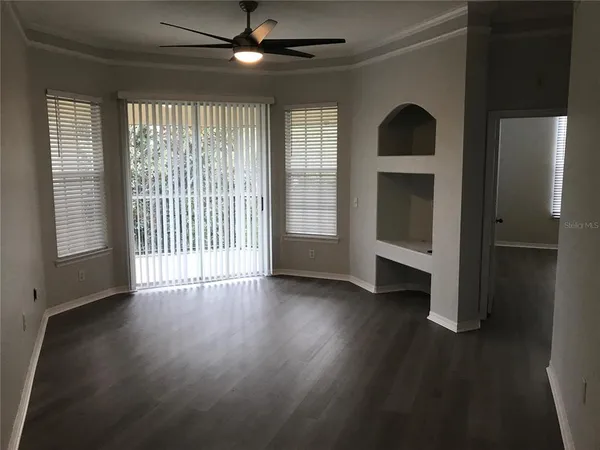 an empty room with wooden floor fan and windows