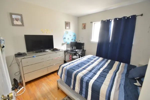 a bedroom with a bed and flat tv screen on the dresser