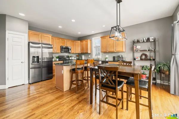 a kitchen with stainless steel appliances kitchen island granite countertop a table chairs and a refrigerator