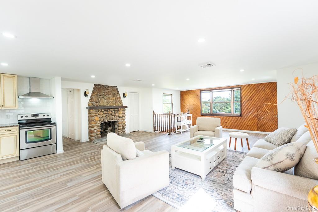 202 2nd Road Wappingers Falls, NY 12590 - Photo 11 of 24 Living area with a stone fireplace, light wood finished floors, recessed lighting, and wooden walls