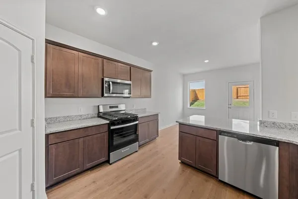 a kitchen with stainless steel appliances granite countertop a stove a sink and a microwave