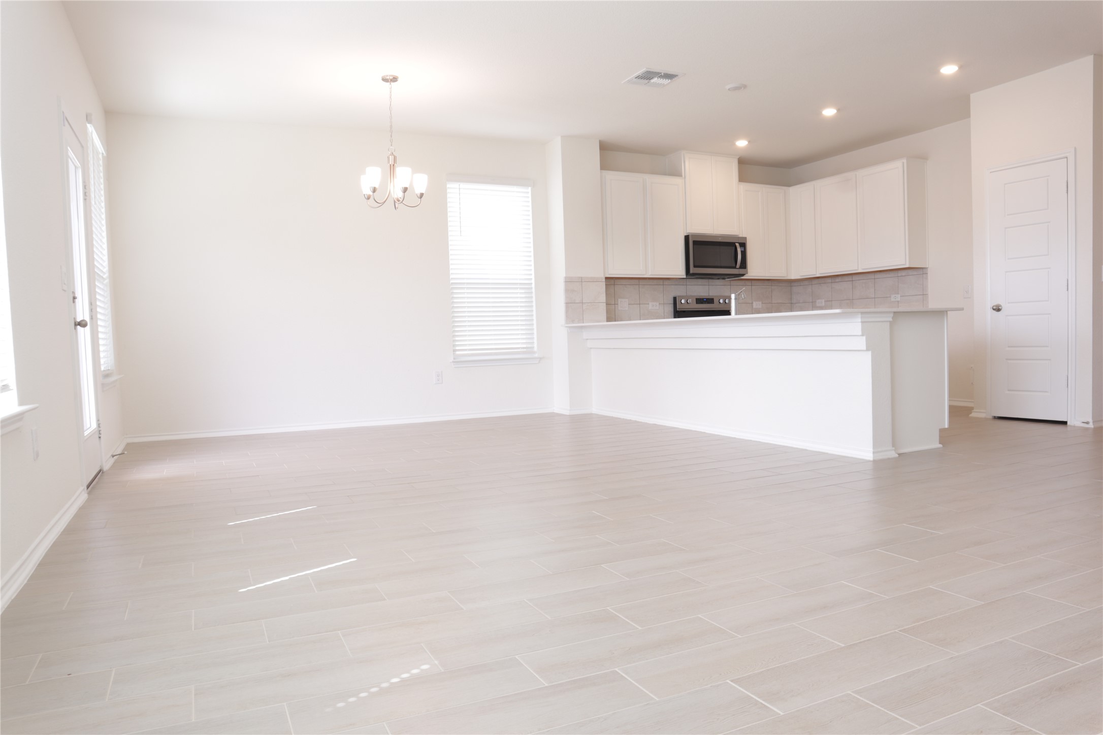 8111 Marigny Way Austin, TX 78744 - Photo 24 of 29 A spacious, open-concept living area with light tile flooring and abundant natural light flows into a modern kitchen.