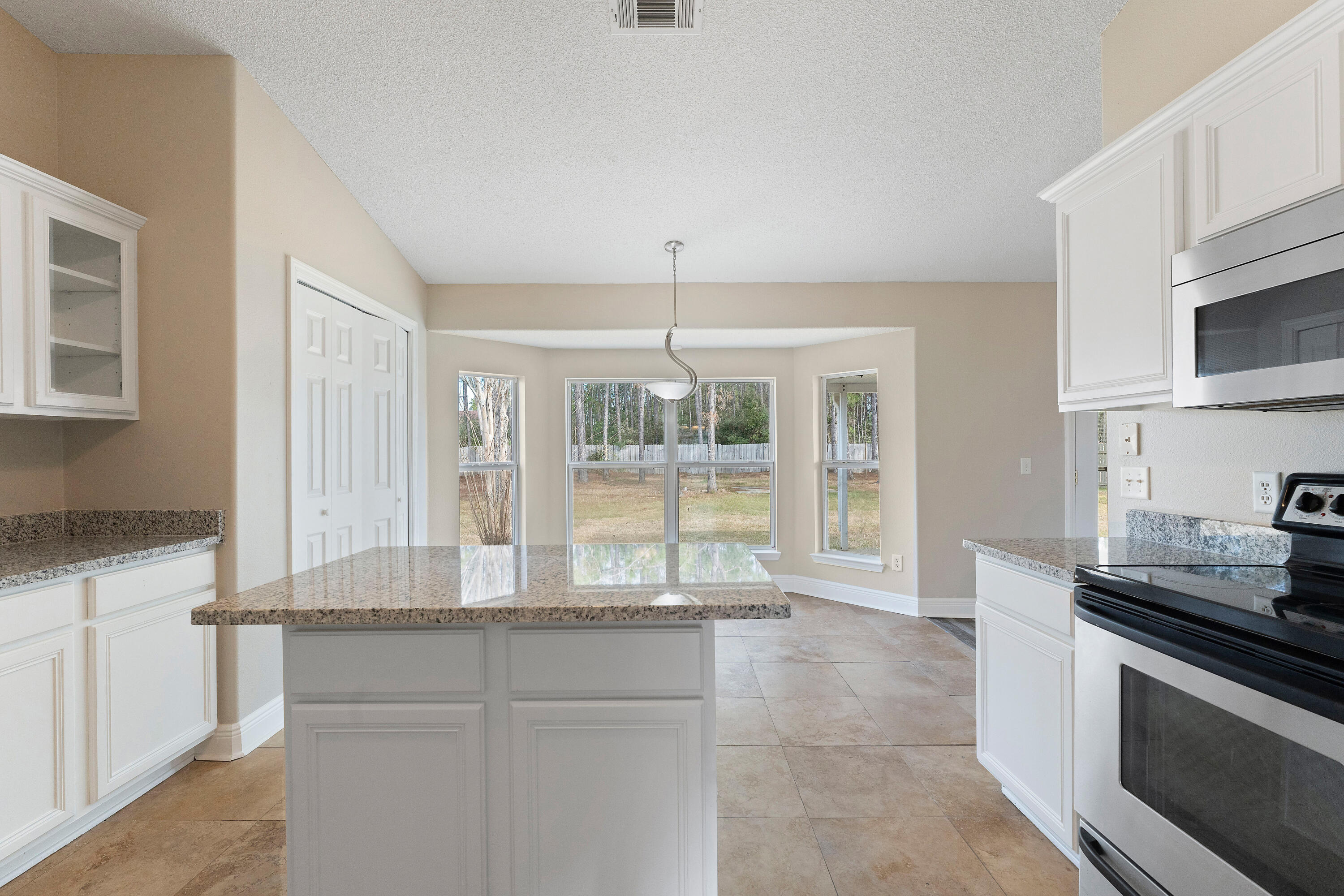 7162 Riverview Road Navarre, FL 32566 - Photo 25 of 33 a kitchen with granite countertop a stove and a white cabinets