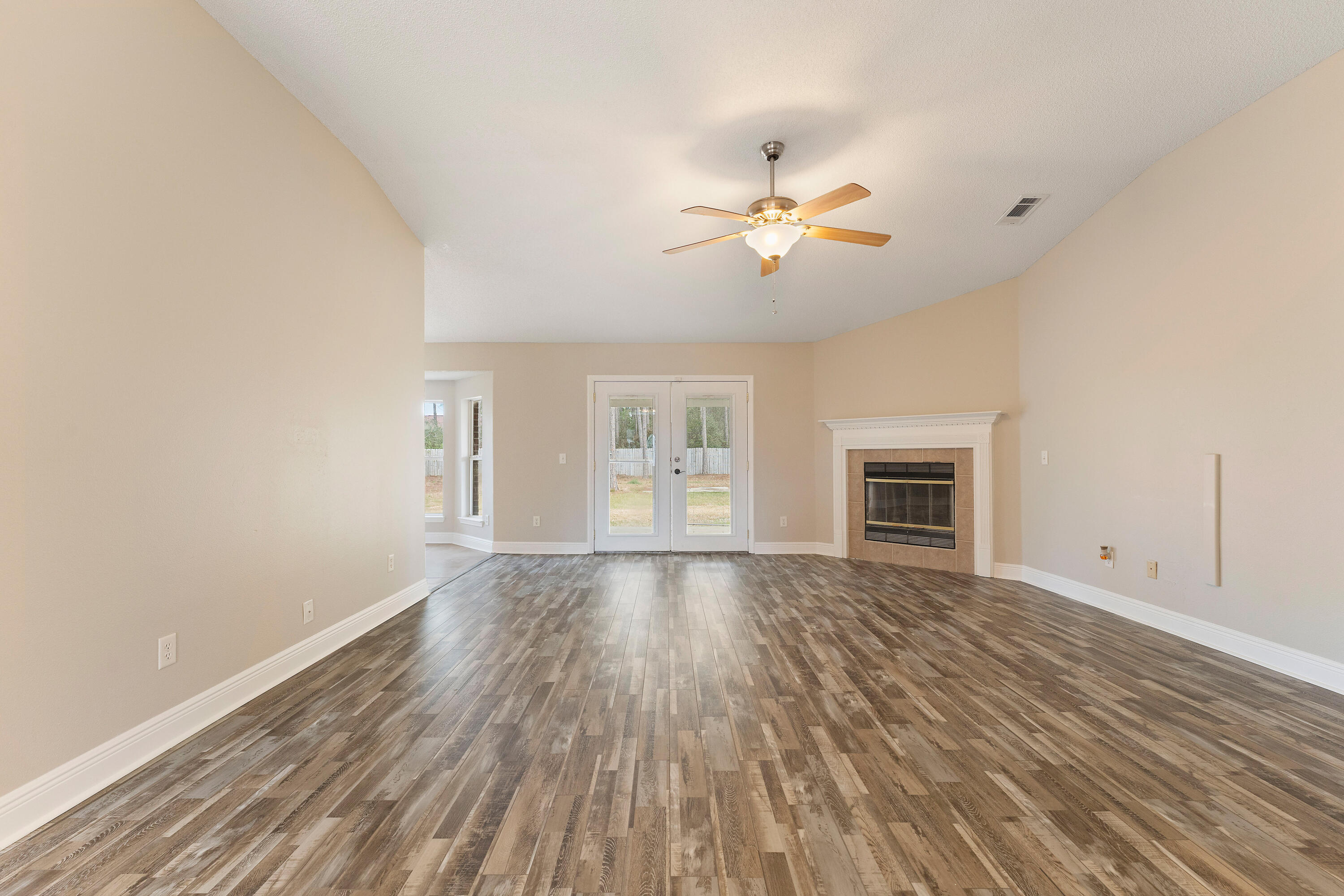 7162 Riverview Road Navarre, FL 32566 - Photo 6 of 33 a view of empty room with wooden floor and fan