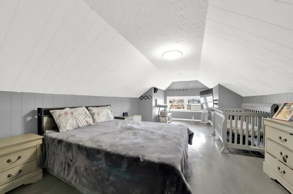 a spacious bedroom with a bed a chandelier and dresser
