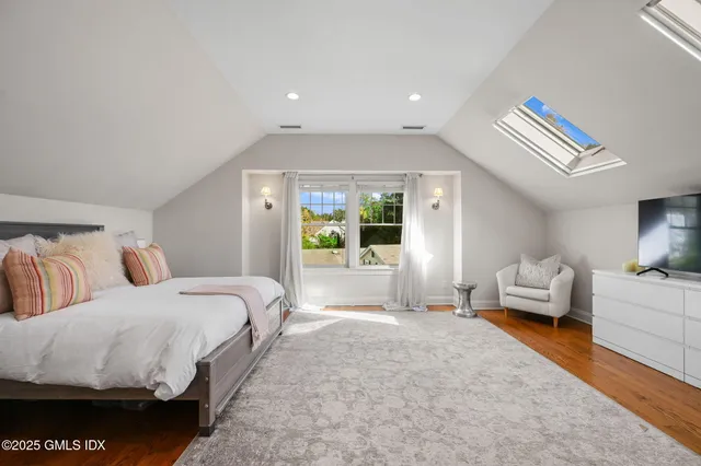 a spacious bedroom with a bed and wooden floor