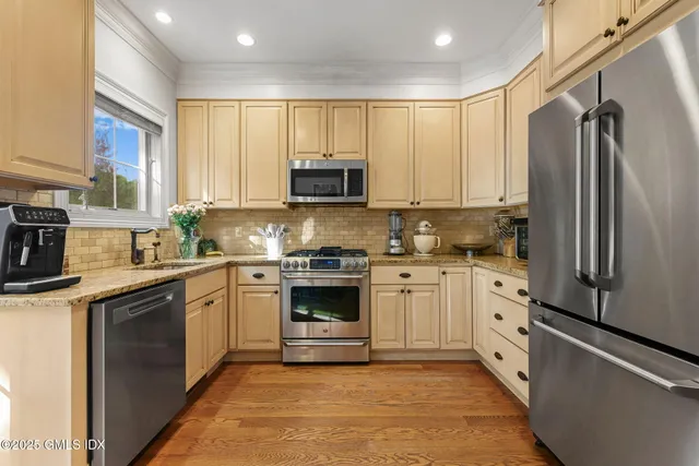 a kitchen with stainless steel appliances granite countertop a stove a sink and a refrigerator