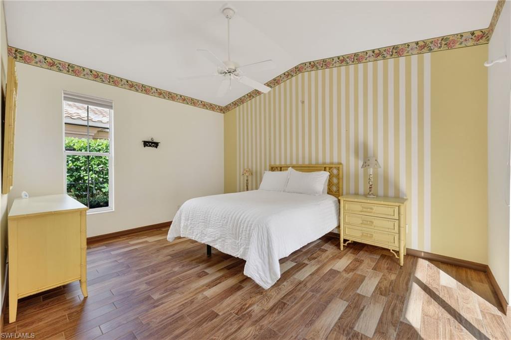 8534 Chase Preserve Drive Naples, FL 34113 - Photo 15 of 44 Bedroom with wood-look tile finished floors, ceiling fan, wallpapered walls, lofted ceiling, and an accent wall