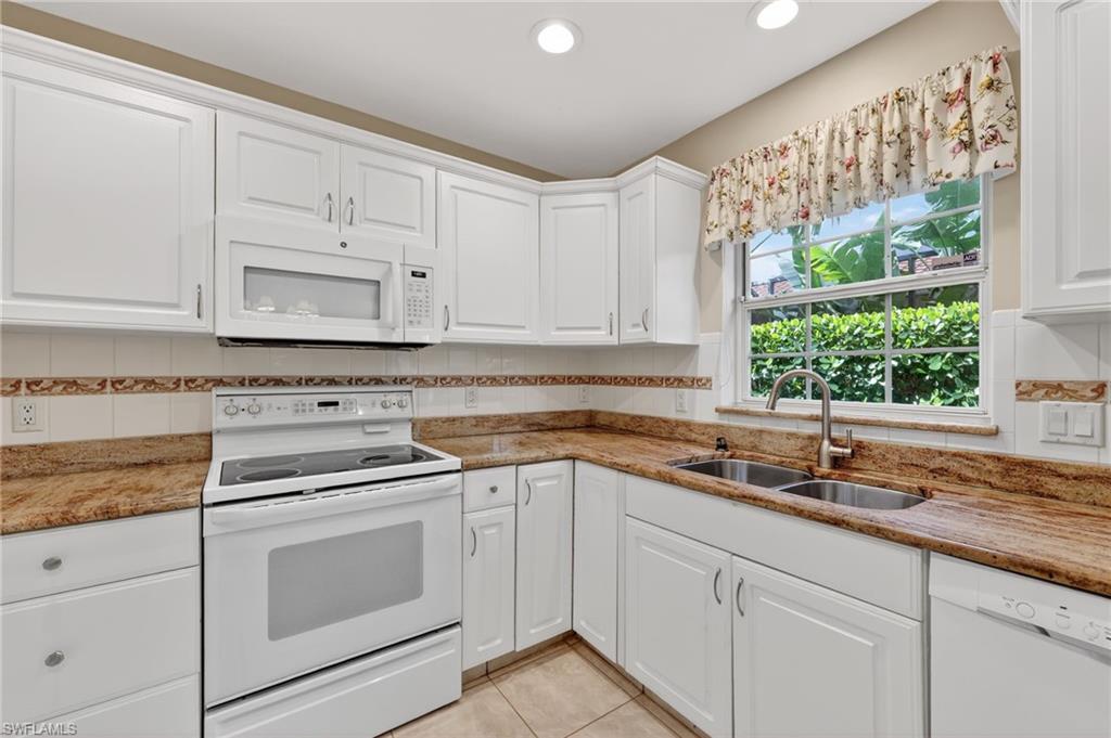 8534 Chase Preserve Drive Naples, FL 34113 - Photo 9 of 44 Kitchen with white appliances, backsplash, light stone countertops, and white cabinetry