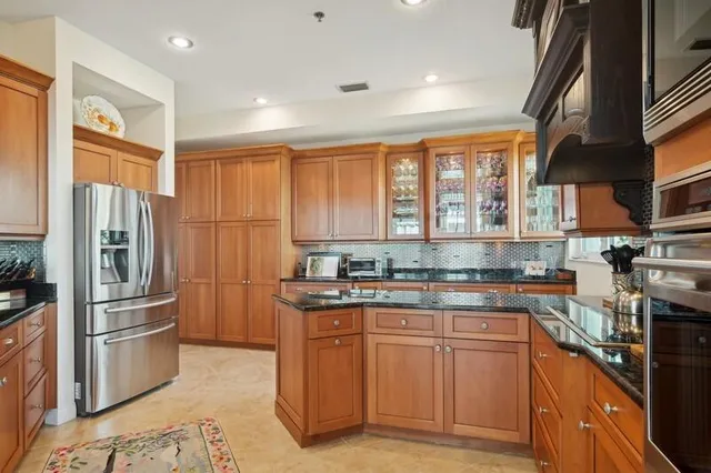 a kitchen with stainless steel appliances granite countertop a refrigerator a sink a stove and white cabinets